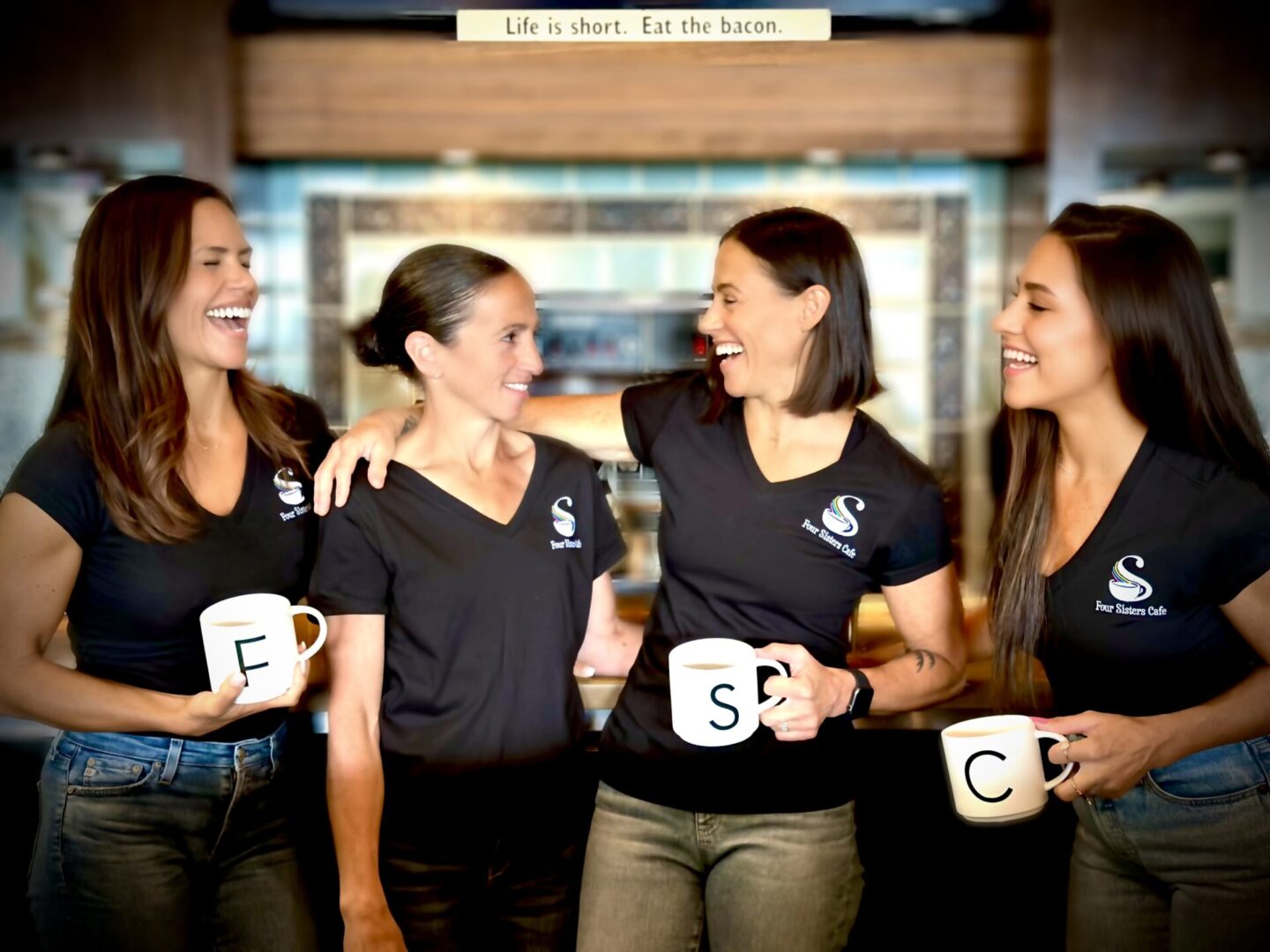 Four women are holding coffee mugs in a group.